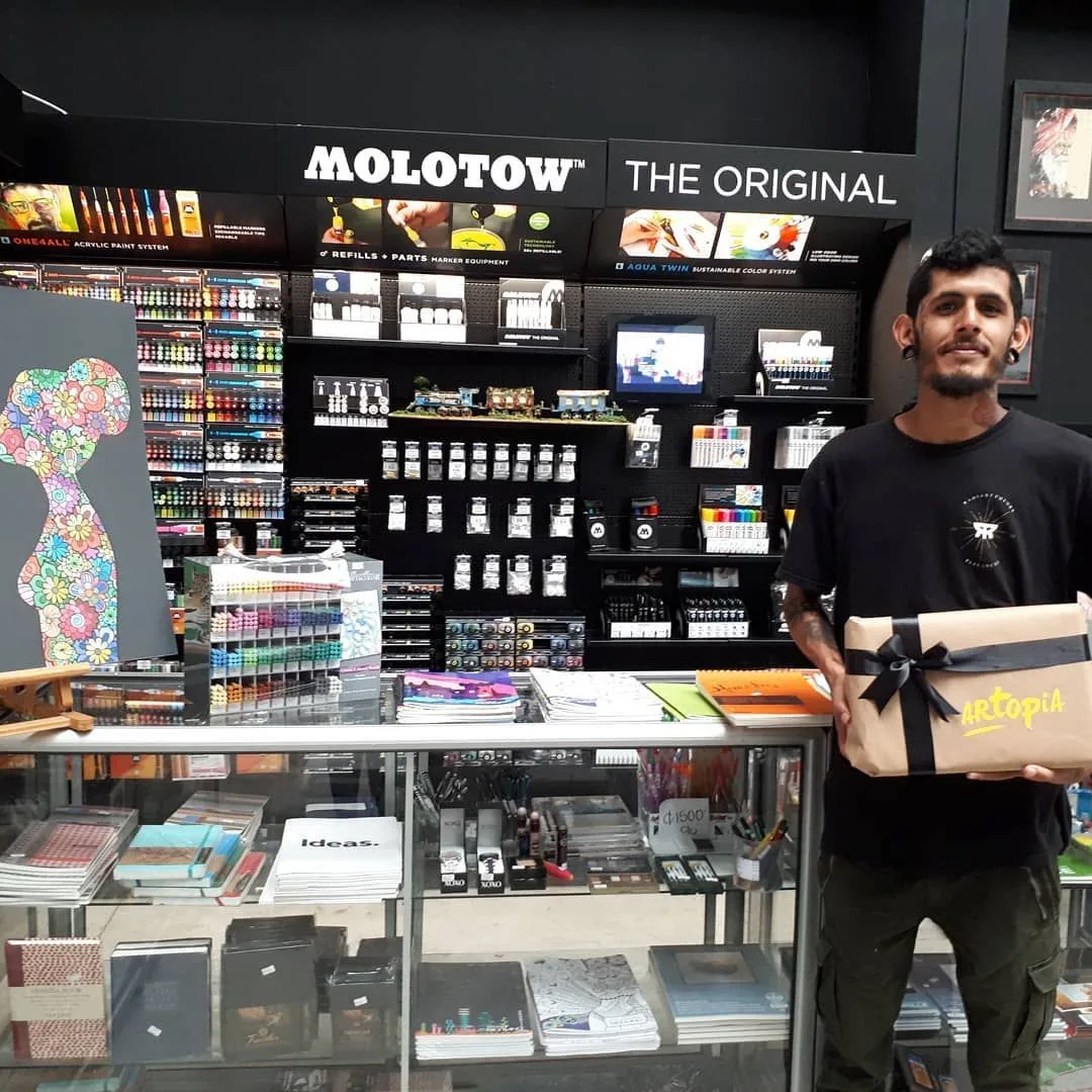 Mostrador de Artopia con el corner de Molotow y un cliente con un regalo envuelto con el logo de Artopia